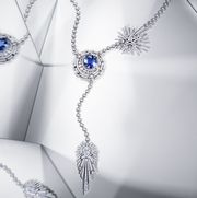 lariat style necklace of blue sapphires encircled with a moon of round cut diamonds and a star in diamonds above it and a pear cut comet in diamonds dangling from it