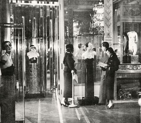 old black and white photo from the 1930s of the show with torso mannequins on stands adorned with jewelry and a couple looking at them holding a program guide