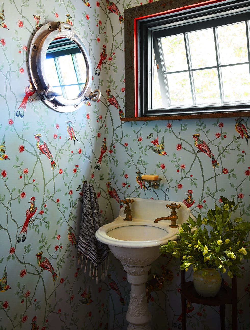 in a powder room is a small circular sink adorned with leaf designs