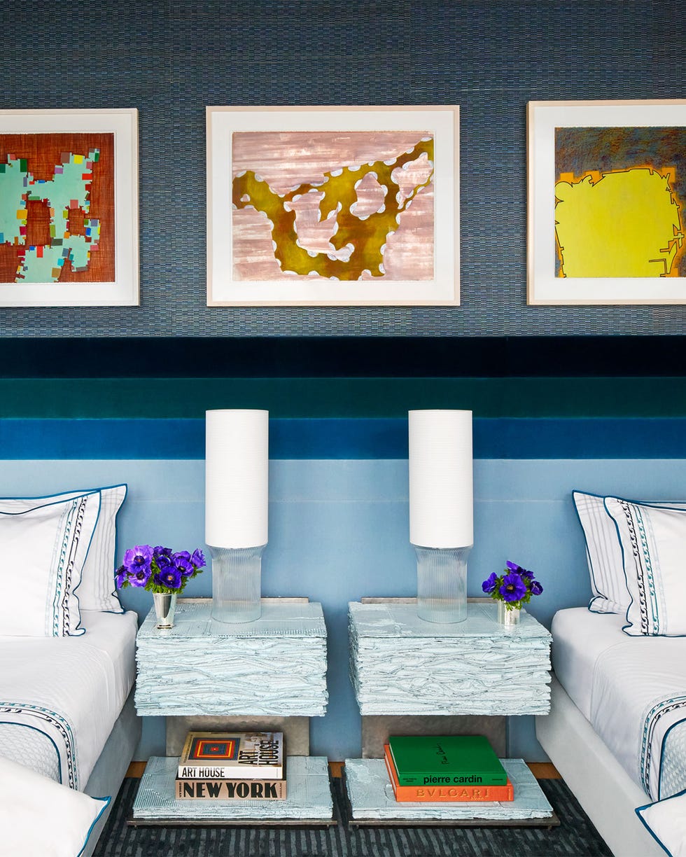 Fox-Nahem – ELLE DECOR a kids bedroom has twin beds dressed in white linens that have a shared headboard in four shades of velvet fabric two night