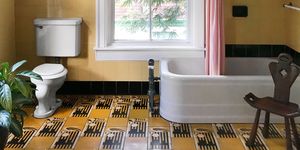 yellow painted bathroom with black and yellow tiled flloor and pink tub curtain and window at center