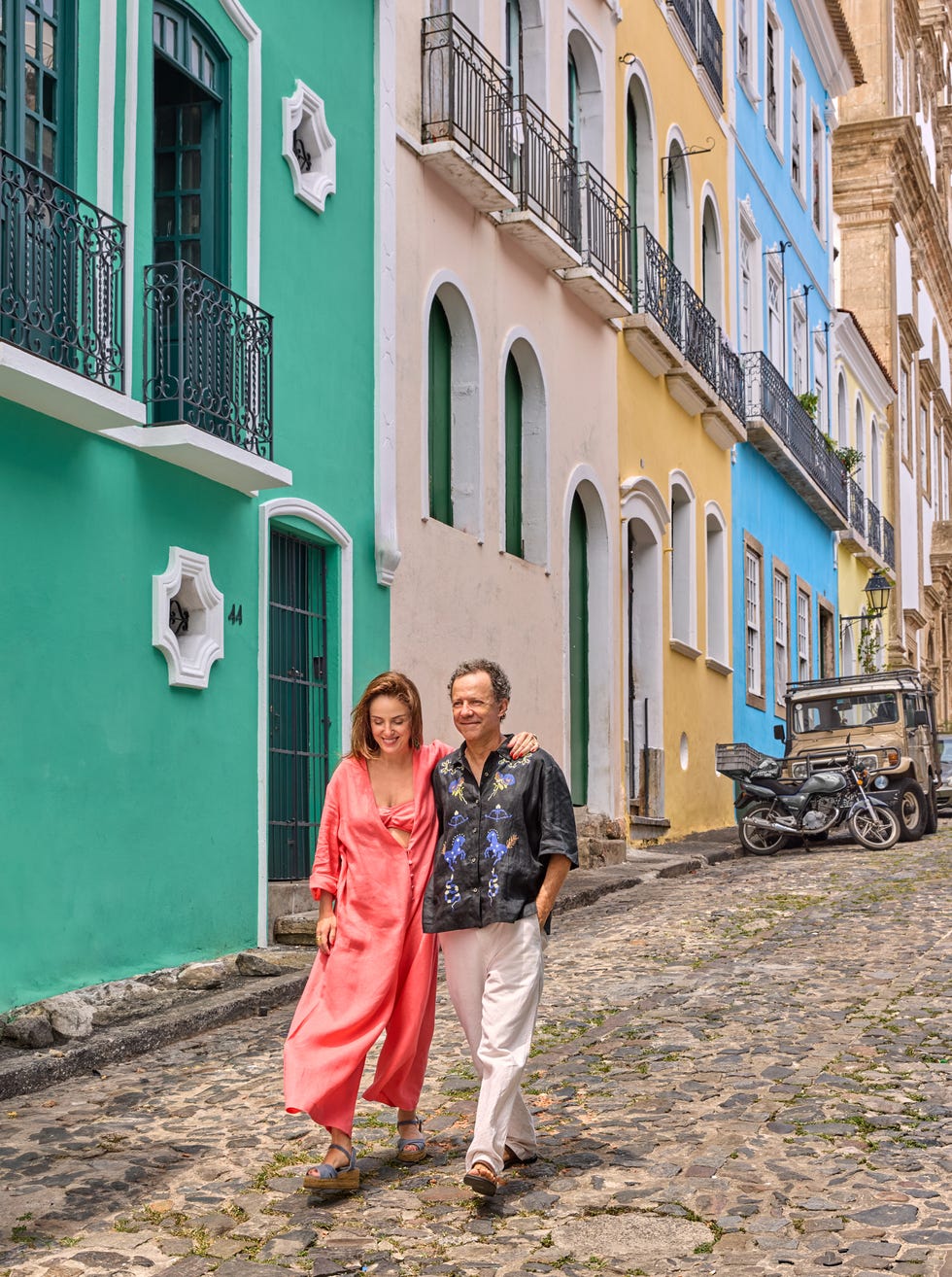 couple walking along a colorful street with historical architecture and cobblestone pavement