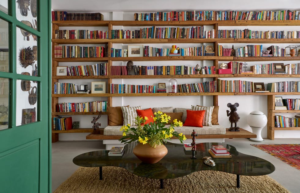 sala de estar aconchegante com uma estante cheia de livros, itens decorativos e uma área de estar