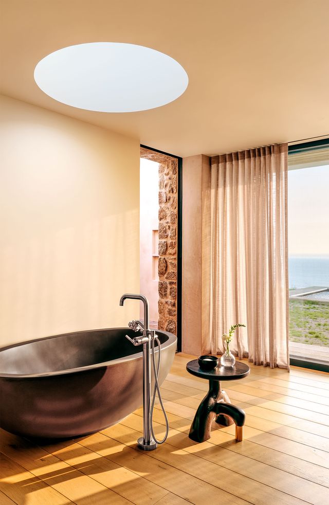 dark standalone tub in bathroom with sliding doors with view