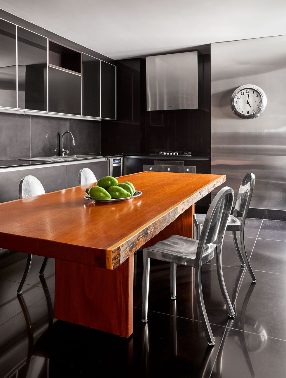 a chrome and black kitchen with a wood dining table