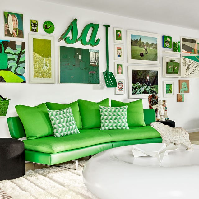 living room with acid green armless sofa and matching and complementary pillows and a large round white cocktail table on a white rug and other green accents on the walls