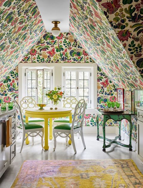 an upstairs dining area with colorful floral wallpaper four chairs around a yellow dining table and an area rug
