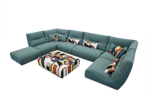 large green wraparound sofa with psychodelic fabric ottoman and decorative pillows