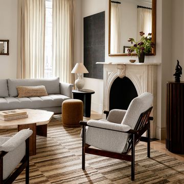 a light colored living room with a fireplace and stripey carpet in various hues of ecru and brown