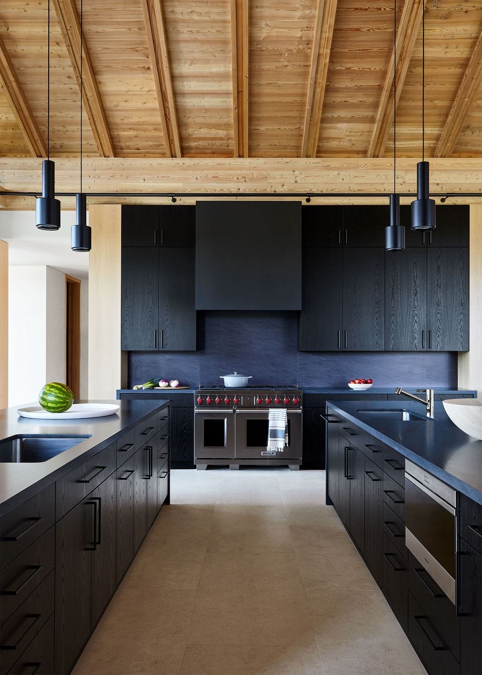 a kitchen with black cabinets and wood ceiling panels