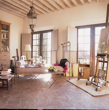rustic room with a daybed and a desk and an art easal and french doors in rustic wood