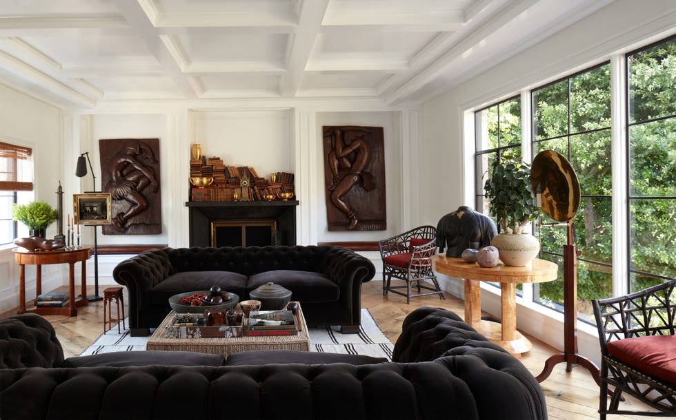 a living room with black tufted sofas and inset molding on the white walls with wooden inset carvings and wood floors