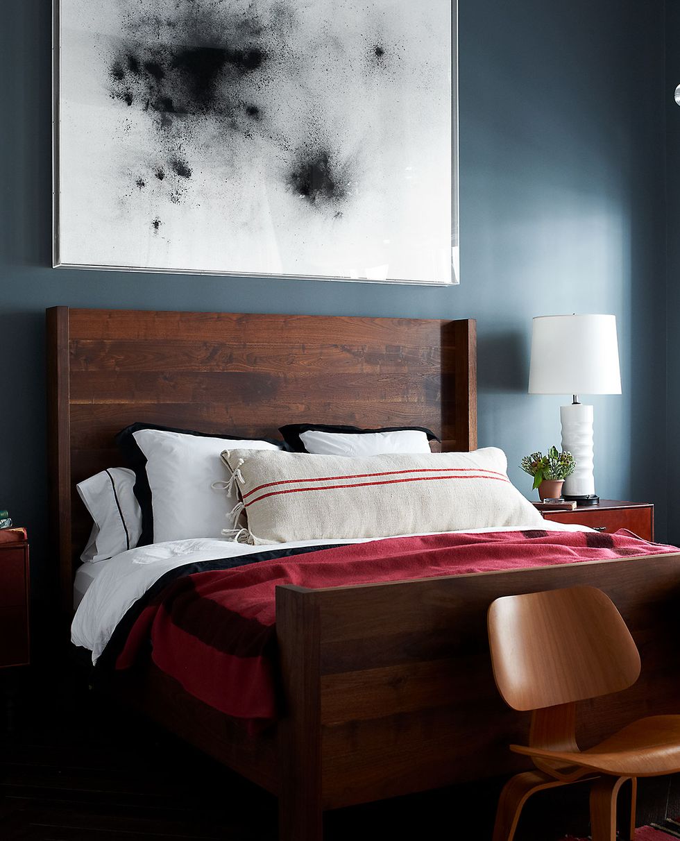 in the master bedroom the bed by bddw is dressed with linens by ralph lauren home and a pillow covered in a vintage grain sack the chairs are by eames the painting is by thilo heinzmann and the walls are painted in farrow and ball modern emulsion in down pip