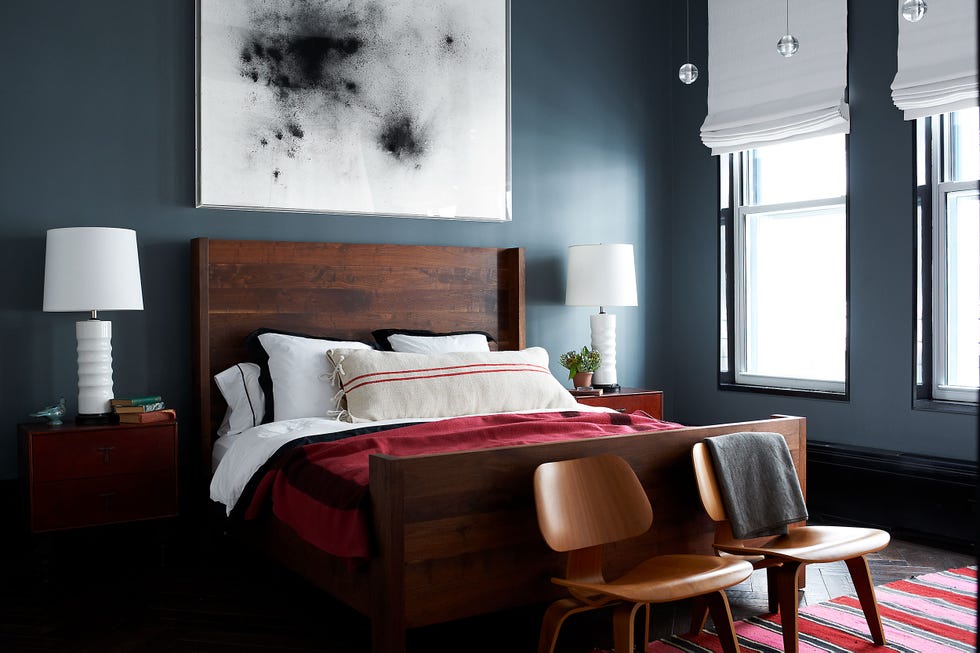 in the master bedroom the bed by bddw is dressed with linens by ralph lauren home and a pillow covered in a vintage grain sack the chairs are by eames the painting is by thilo heinzmann and the walls are painted in farrow and ball modern emulsion in down pip