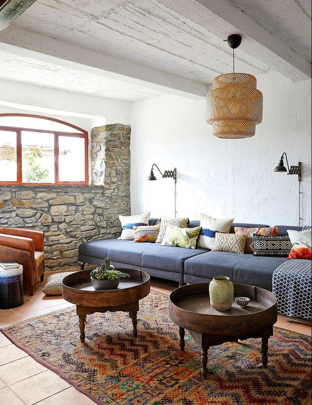 living room with blue sofa, stone wall, and large red rug