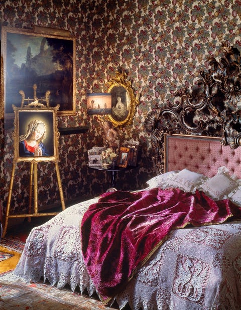 bedroom with patterned wall covering, easel print of virgin mary, and large bed