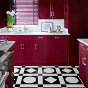 kitchen with red cherry cabinets and white marble counters and black and white geometric floor