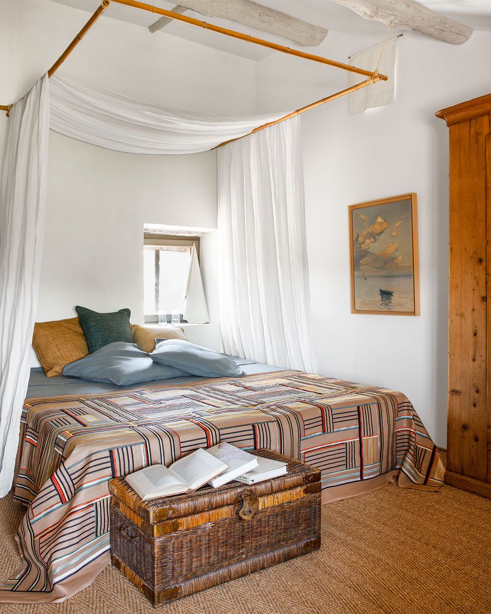 The rooms have beds canopied with light linens, a variety of plain cross-striped comforters and pillows, wicker trunks at the foot of the bed, and whitewashed beams on the ceiling.