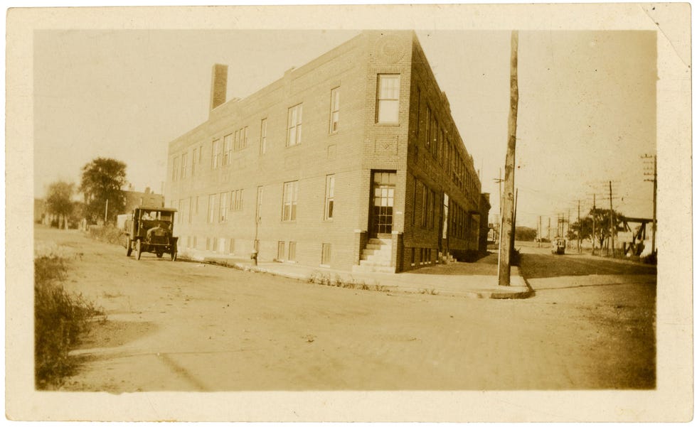 historic brick building on a street with an early model truck parked nearby