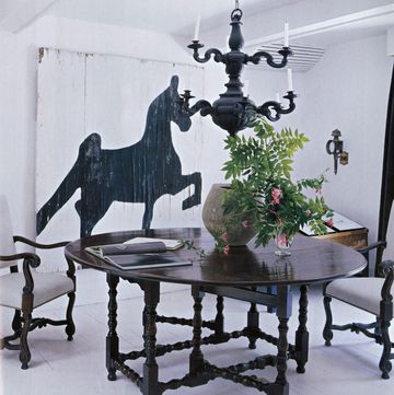an oak gateleg wake table by scottish connection antique armchairs a baroque style chandelier and a painted barn door in the dining room