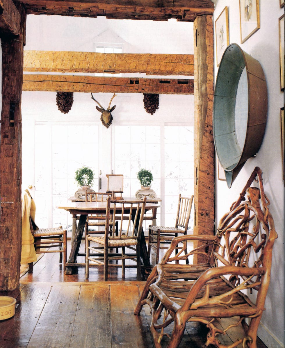 open area with thorn bench in foreground and a small table at back in a window room and heavy beams
