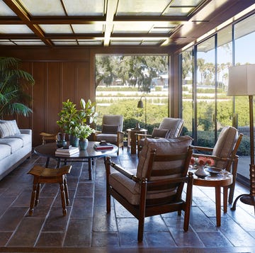 a paneled living room with simple mission furniture and a large glass wall on two sides