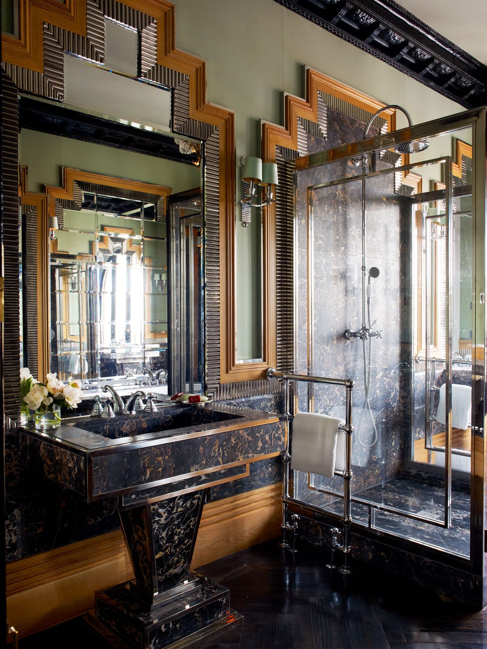 elegant bathroom with stepped moldings of carved walnut, steel, and silver leaf and paned glass and art deco designs on the shower doors