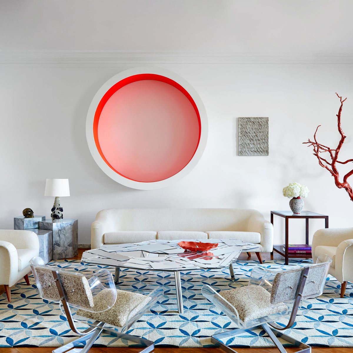 Dining area with a white round table and chair sofa in the center and a large round pink and white artwork on the wall