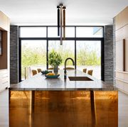 sleek open kitchen with built in cabinetry and center island with a golden base