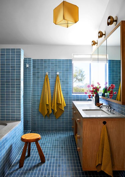 blue tiled bathroom with yellow towels and small stool