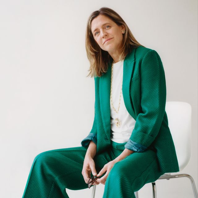 designer on a chair dressed in a green flowy pantsuit and white shirt
