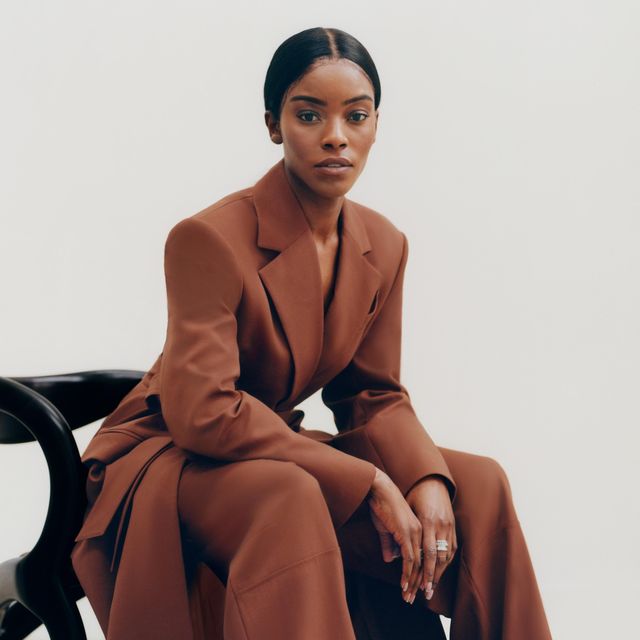 designer sitting looking at the camera in a gorgeous chocolate color long jacket and matching pants