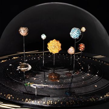 a glass enclosed solar system made up of jewels on pins in a black starry base with knobs a the bottom