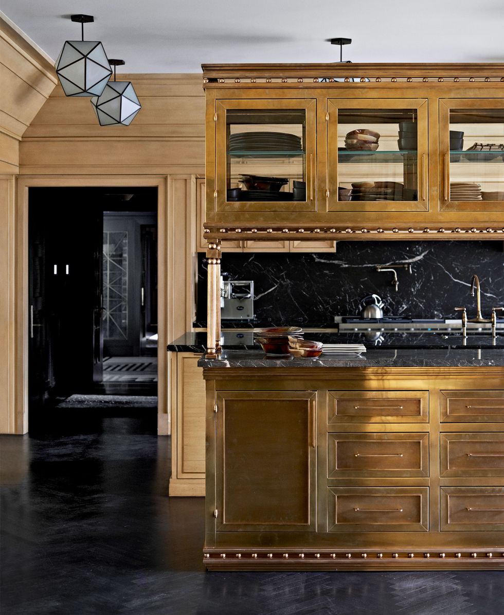 shiny golden wood cabinetry in kitchen with black marble countertop and large island and black floors