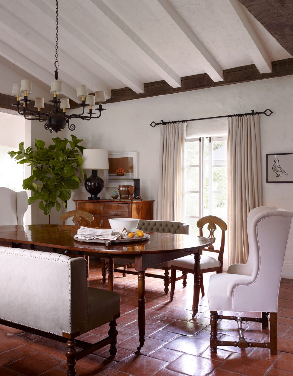 custom made leather benches and a pair of swedish wing chairs from the 1760s surround the directoire dining table a biedermeier chest of drawers holds a lamp by william haines