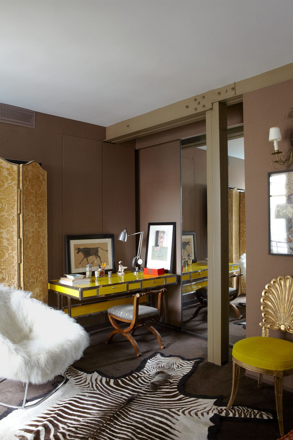 bedroom detail dressing area with zebra skin run and white floofy chair and a a yellow chair with scallop back and a yellow l