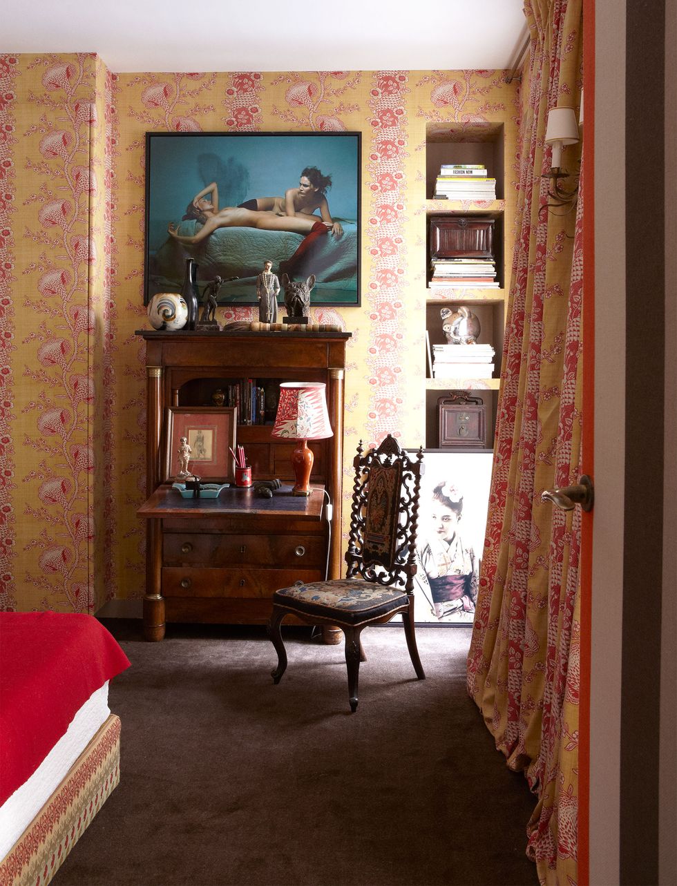 detail of guest room with a door with curtain on the right and a secretary with intricate chair and a large painting on the wall overhead