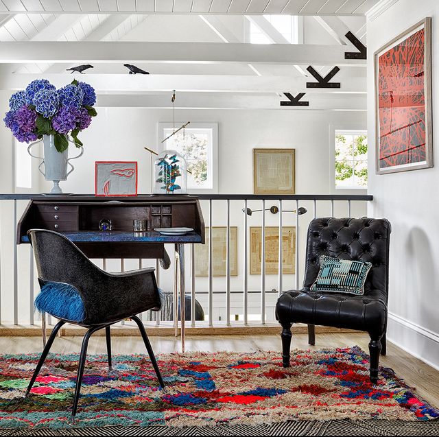 landing with small table, rug, and chairs overlooking room with art on walls