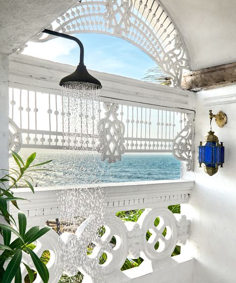 white outdoor shower with moroccan scroll railing overlooking  the water