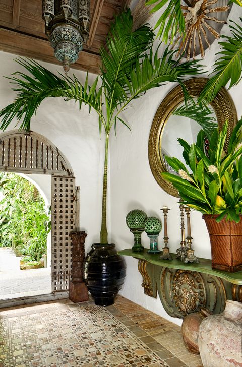 entryway with large potted plant, green table mounted to the wall, large black vase and moroccan panels around the door