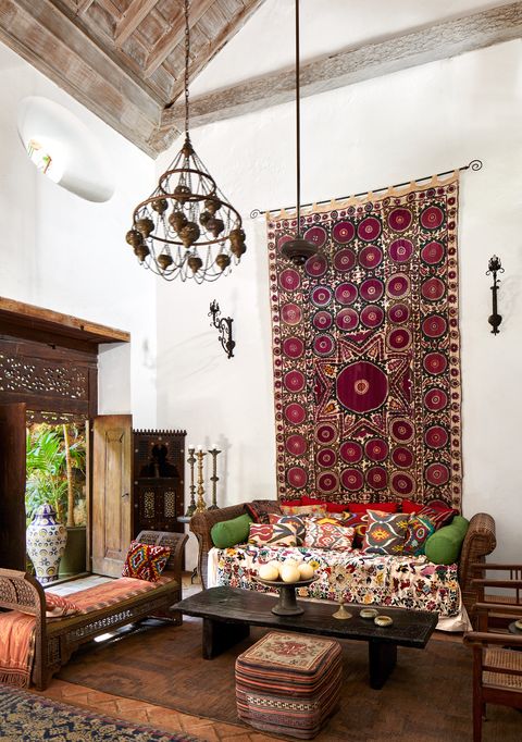 living area with  moroccan bench, a turkish pouf, and sconces and a large drapery hanging behind sofa on wall