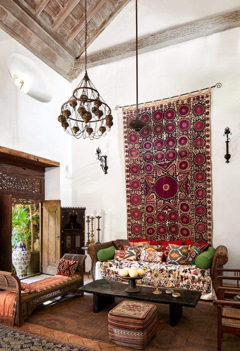 living area with  moroccan bench, a turkish pouf, and sconces and a large drapery hanging behind sofa on wall