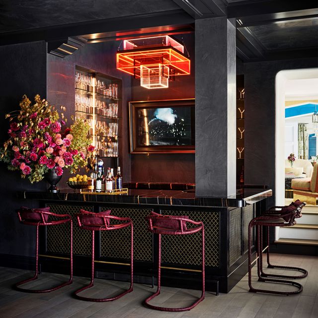 dark moody bar with pink flowers and pink barstools and a neon light by ken fulk photographed by douglas friedman