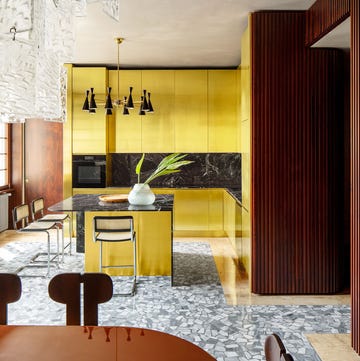 kitchen with shiny brass cabinetry and terrazzo floor and vintage stools at island