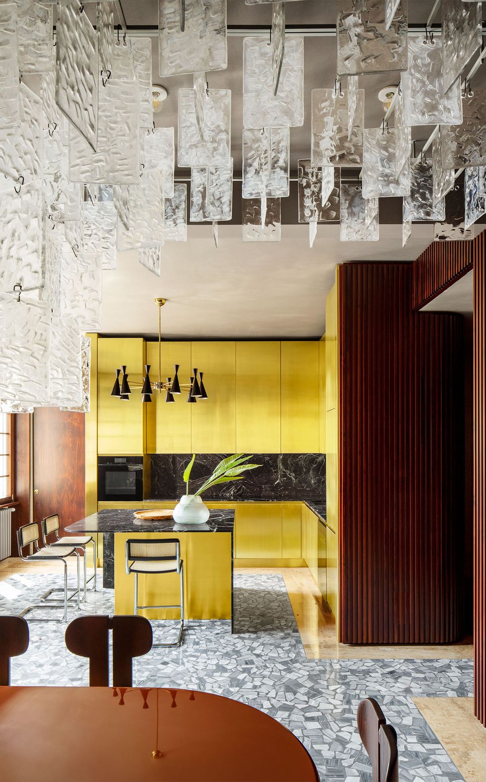 kitchen with shiny brass cabinetry and terrazzo floor and vintage stools at island
