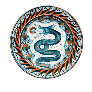 plate with dark blue and orange waves around the outside perimeter and a blue snake gruesomely devouring a red haired baby