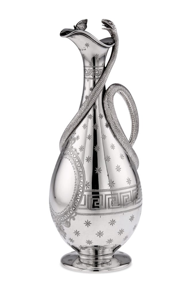 silver wine jug with etched stars on it and a silver snake entwined from the lip to the center to become the handle and a tiny butterfly perched delicately on the rim of the jug