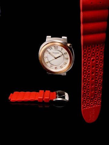 a gold and silver watch with a red band on a black surface