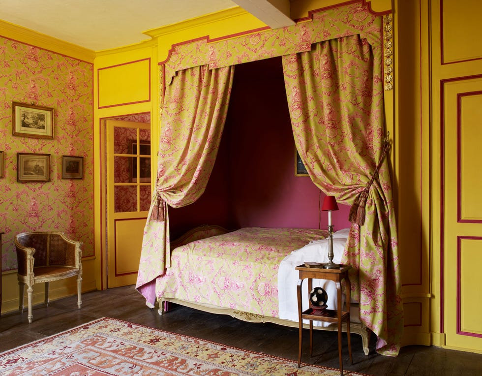 interior of a brightly decorated yellow painted bedroom featuring an inset captain's bed with matching yellow pattern canopy and curtains