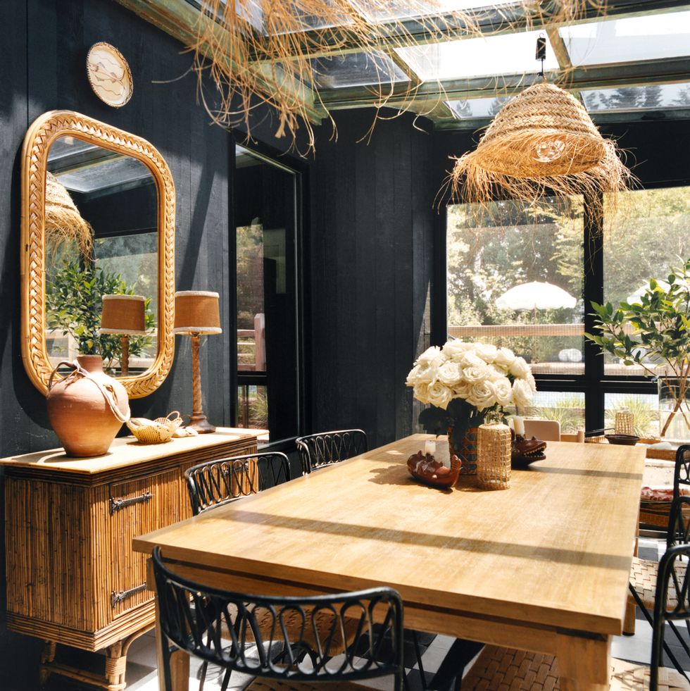 dinining room with black walls, wood table, bamboo sideboard and hanging lamps